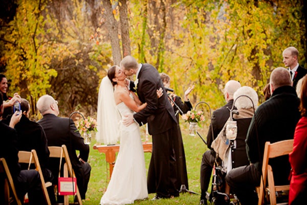 Husband and wife sharing a kiss during their outdoor wedding ceremony. 