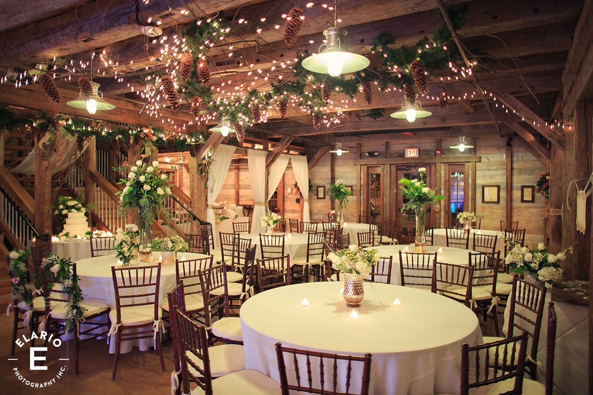 Reception area inside of Pat's Barn set up with decorated tables, lights, pinecones and florals. 