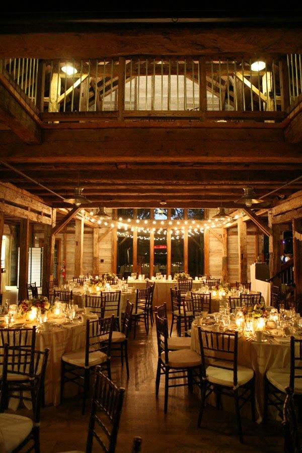 Inside of Pat's Barn reception are at night with soft lights and decorated tables. 