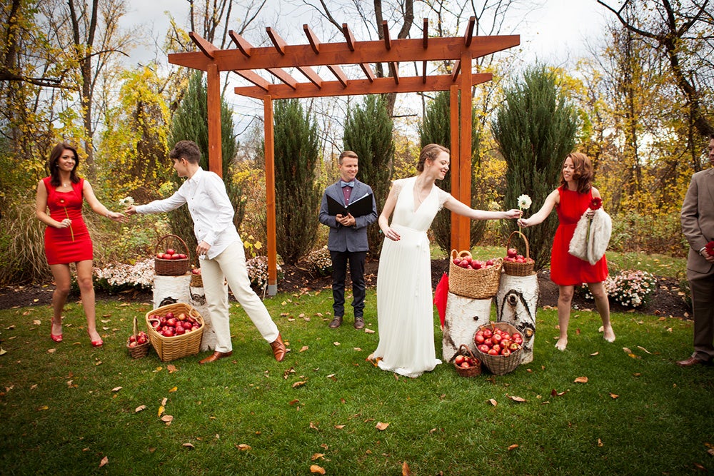 Wedding party posting with flowers and apples in front of an archway outside of Pat's Barn.