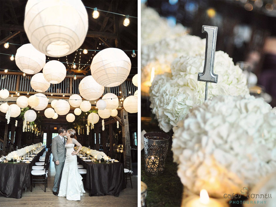 (1) Couple posing in front of black and white decorated tables with paper lanterns inside of Pat's Barn. (2) Close up of white flowers on tables with 